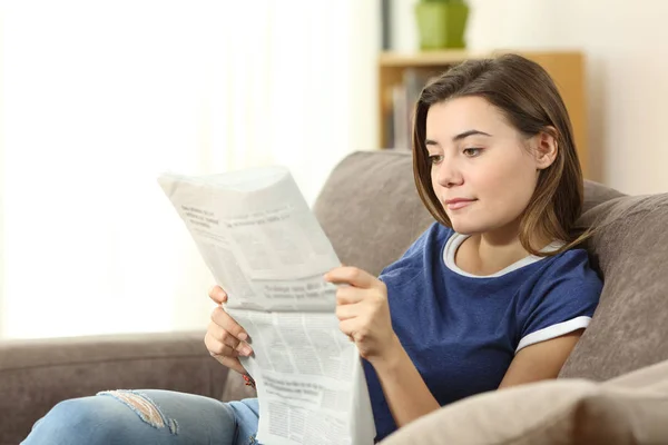 Adolescente sério lendo um jornal em casa — Fotografia de Stock