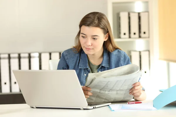 Stażysta porównanie wiadomości w laptopie i gazety — Zdjęcie stockowe