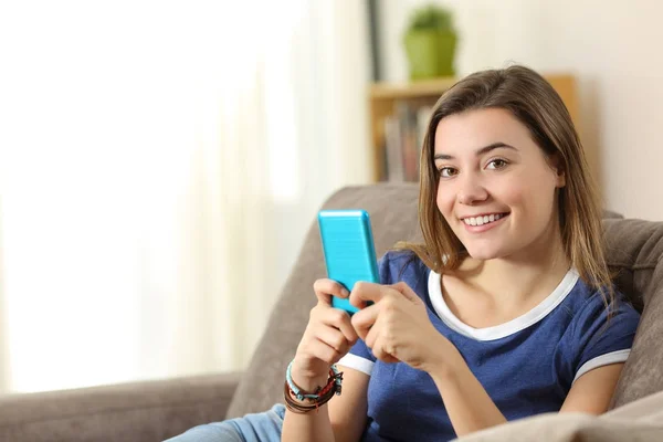 Adolescente feliz detém um telefone inteligente olhando para você — Fotografia de Stock