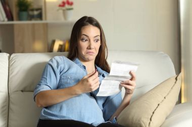 Distrustful pregnant lady reading a leaflet before take a pill clipart