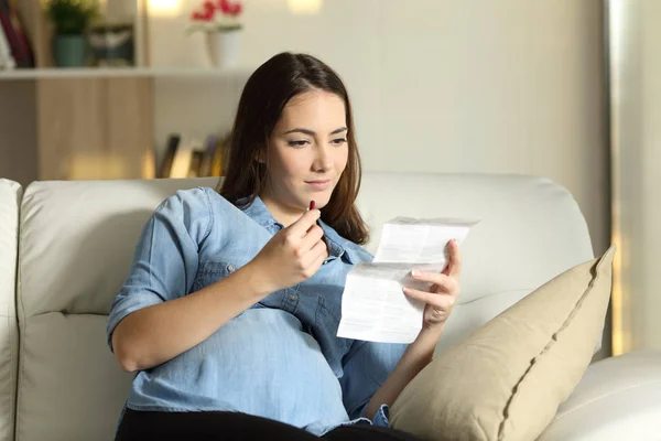 Беременная женщина читает брошюру перед тем, как принять таблетку — стоковое фото