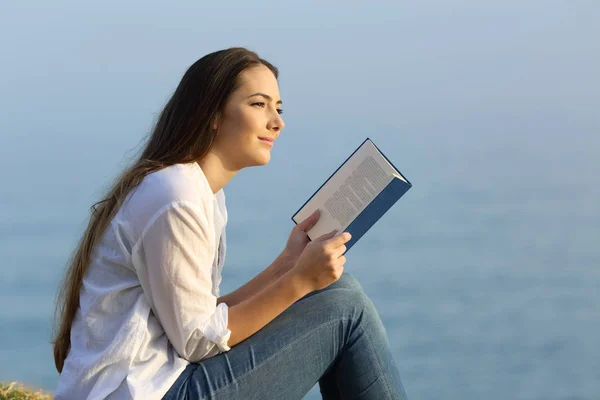 Vrouw droomt lezen van een boek op het strand — Stockfoto