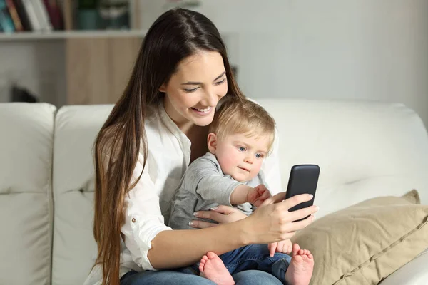 Anne ve bebek bir akıllı telefon ile oynamak — Stok fotoğraf
