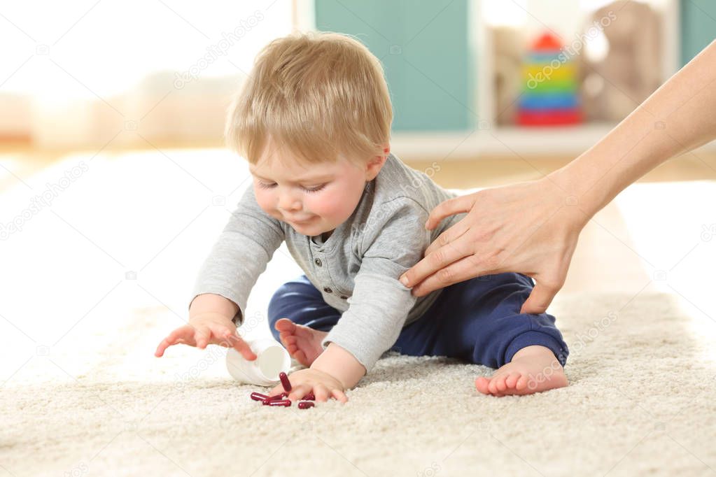 Mother hand preventing the baby from eating pills