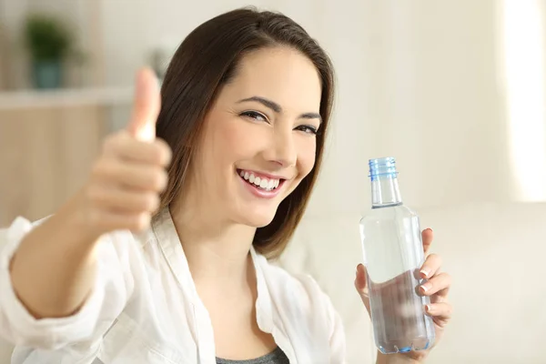 Gelukkig meisje houdt een waterfles gebaren duimschroef opwaarts — Stockfoto