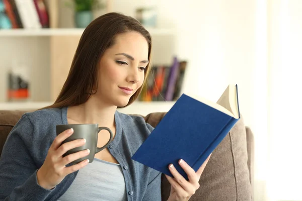 Dame détendue lisant un livre et tenant une tasse — Photo