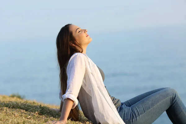 Розслаблена жінка дихає свіжим повітрям, сидячи на траві — стокове фото