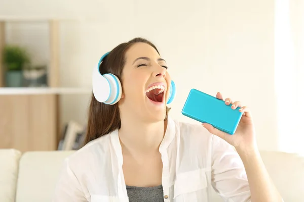 Adolescente cantando ouvir música em um sofá — Fotografia de Stock