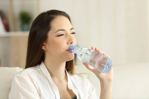 Mujer bebiendo agua de una botella en casa — Foto de Stock