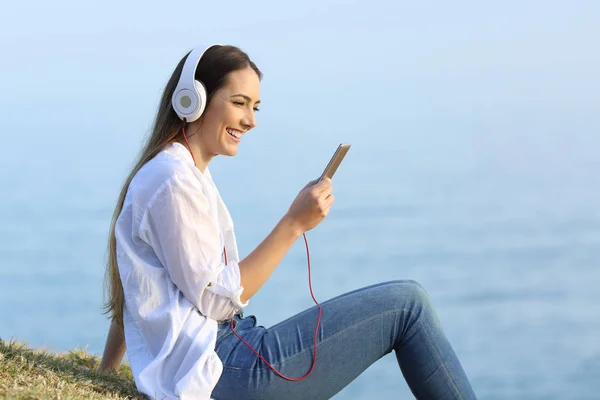 Kvinna Lyssna på avkopplande musik på stranden — Stockfoto