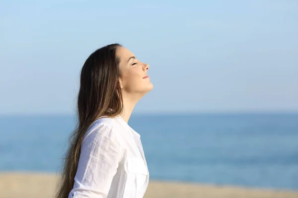Женщина расслабляется дыша свежим воздухом на пляже — стоковое фото