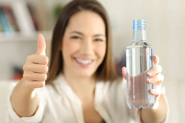 Vrouw het tonen van een fles water met duimen omhoog — Stockfoto