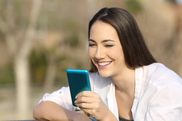 Mulher usando um telefone inteligente azul ao ar livre — Fotografia de Stock