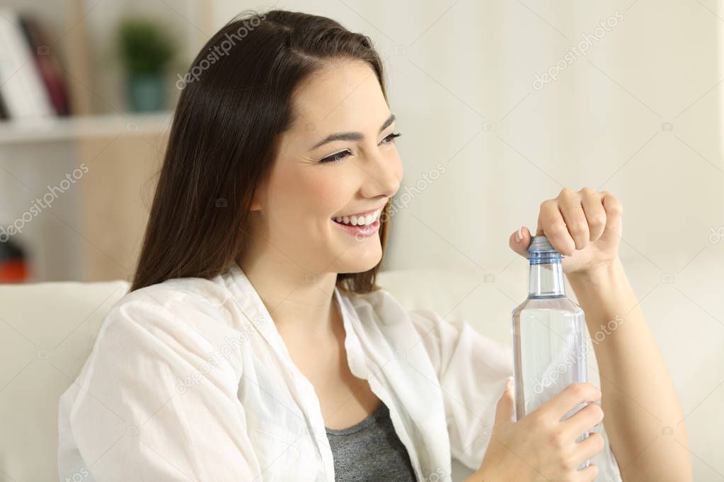 Woman opening a bottle of water at home