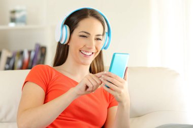 Kız evde telefon ve kulaklık ile müzik dinlemek