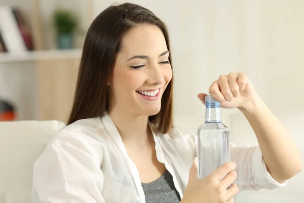 Lady, otwierając butelkę wody na kanapie — Zdjęcie stockowe