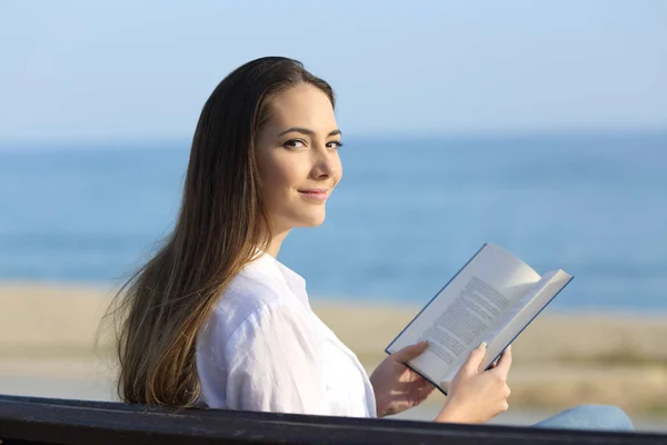 Vrouw een boek lezen en bekijken van camera — Stockfoto