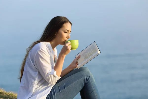 Mulher bebendo café e lendo um livro ao ar livre — Fotografia de Stock