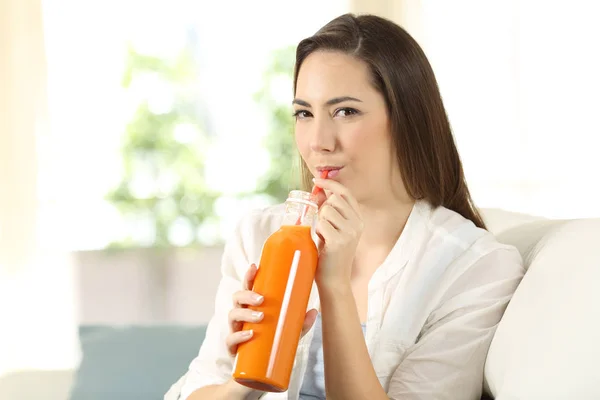 Chica bebiendo una zanahoria o jugo de naranja de una botella —  Fotos de Stock