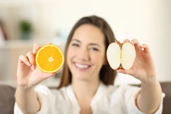 Женщина показывает апельсин и яблоко — стоковое фото