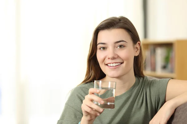 Feliz adolescente sosteniendo un vaso de agua mirándote — Foto de Stock