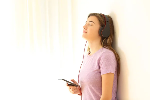 Relaxed teen listening to music on leaning a wall — Stock Photo, Image