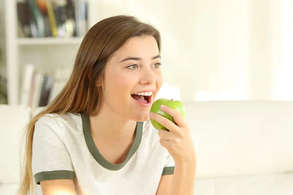 Teen eating an apple on a couch at home — Stock Photo, Image