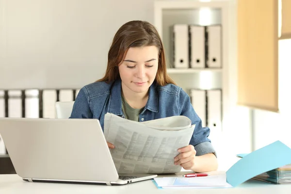 Joven aprendiz leyendo un periódico en la oficina —  Fotos de Stock