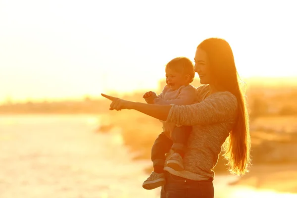 Mãe e filho felizes olhando para longe ao pôr do sol — Fotografia de Stock