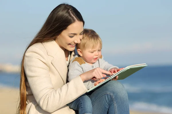 Kid learning and mother showing a book — Stock Photo, Image