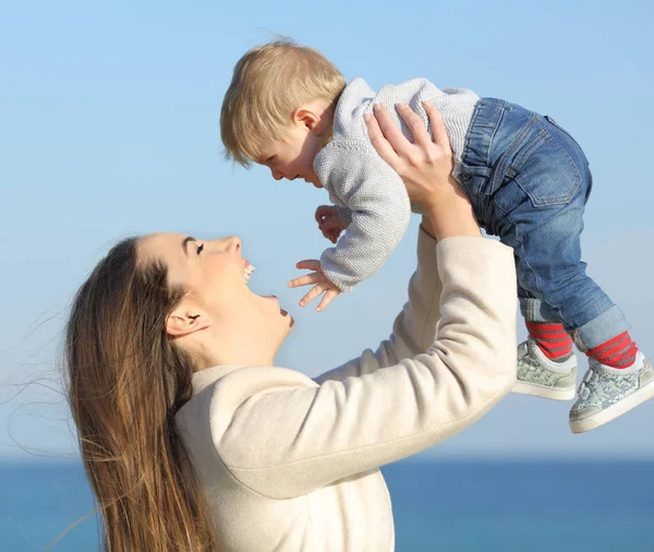 Mor att höja hennes baby son utomhus på stranden — Stockfoto