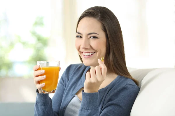 Chica sosteniendo un jugo de naranja y una píldora mirándote — Foto de Stock