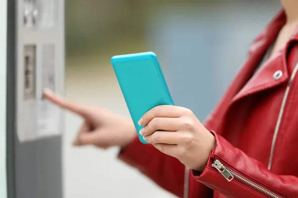 Menina usando um telefone inteligente para pagar em uma máquina de pagamento — Fotografia de Stock
