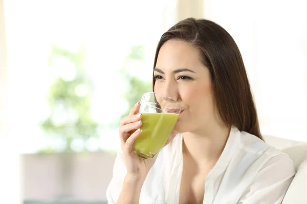 Mujer bebiendo un jugo de verdura verde en casa — Foto de Stock
