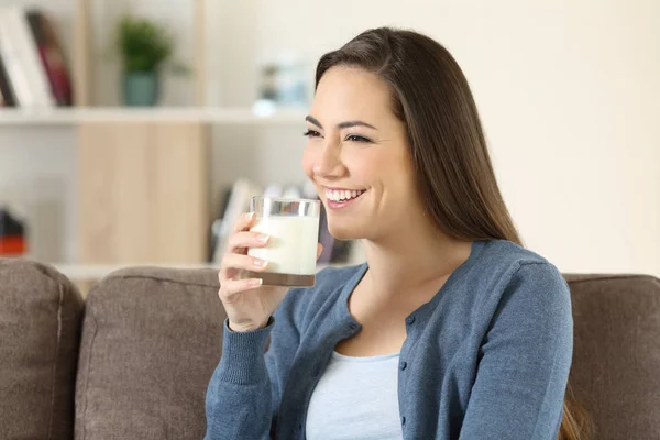 Mujer sosteniendo un vaso de leche en un sofá — Foto de Stock
