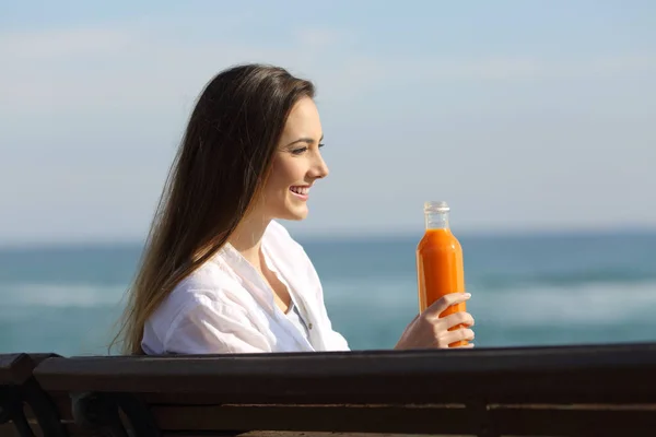Mujer sosteniendo una botella de jugo de naranja y mirando hacia otro lado —  Fotos de Stock