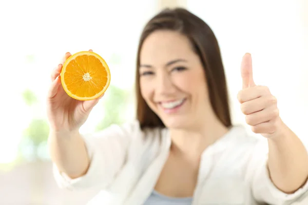 Woman showing half orange with thumbs up — Stock Photo, Image