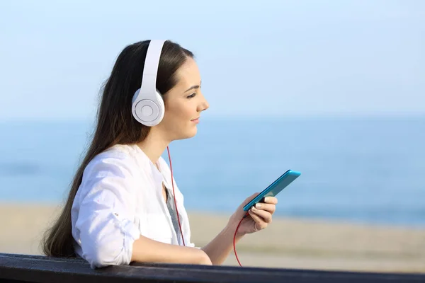 Девушка слушает музыку расслабляясь на пляже — стоковое фото