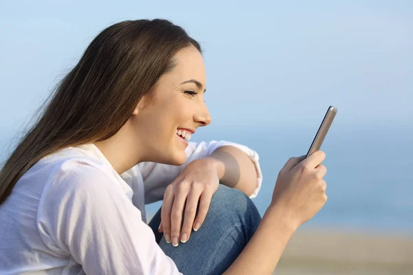 Девушка улыбается, читая на онлайн контенте в смартфоне — стоковое фото