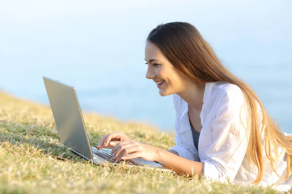 Chica escribiendo en un portátil en la hierba — Foto de Stock