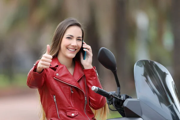 Motociclista feliz con pulgares en el teléfono —  Fotos de Stock