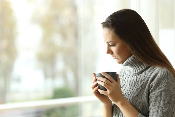 Traurige melancholische Frau mit einem Becher zu Hause — Stockfoto