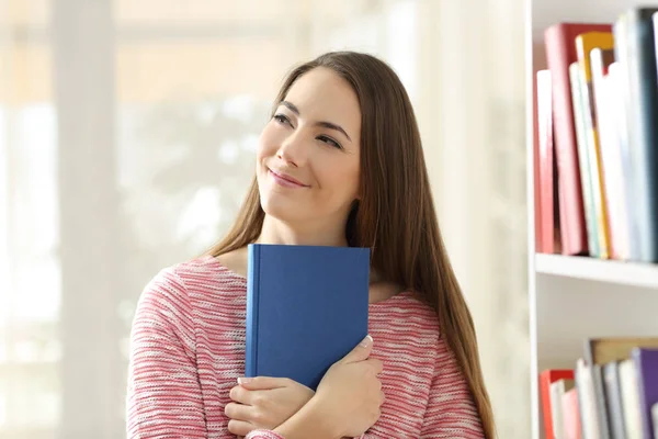 Woman dreaming holding a book showing cover — Stock Photo, Image