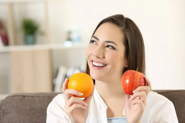 Mujer preguntándose acerca de manzana y naranja — Foto de Stock