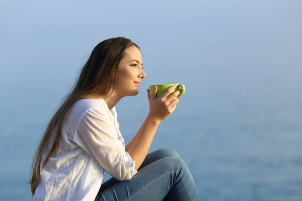 Donna con una tazza rilassante al tramonto sulla spiaggia — Foto Stock