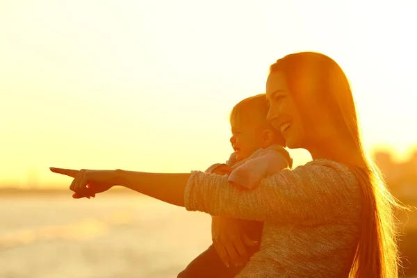 Mãe e filho filho olhando para longe ao pôr do sol — Fotografia de Stock