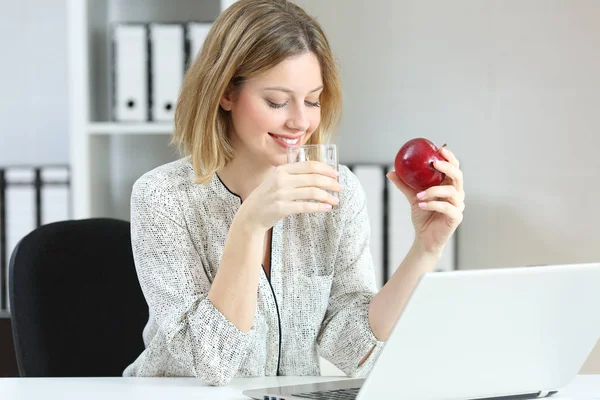 Работник офиса пьет воду и ест яблоко — стоковое фото