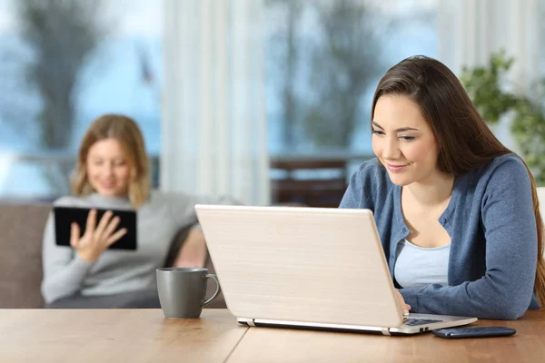 Zwei entspannte Mitbewohner mit mehreren Geräten zu Hause — Stockfoto