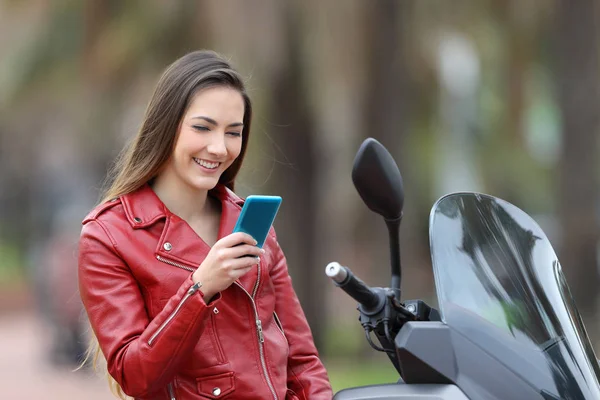 Motociclista comprobando el teléfono en su moto en la calle —  Fotos de Stock