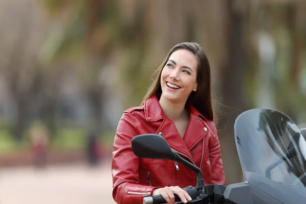 Biker thinking looking at side on her motorbike — Stock Photo, Image